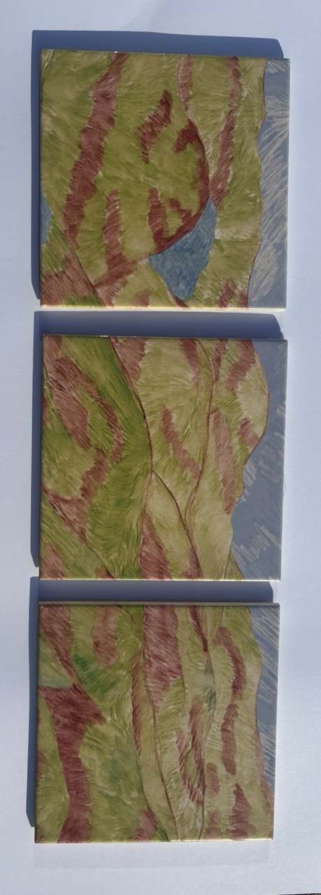 Three wooden panels arranged vertically, each featuring a swirling abstract design in shades of green and red, with some blue accents. The panels have a smooth finish and are placed against a light background.