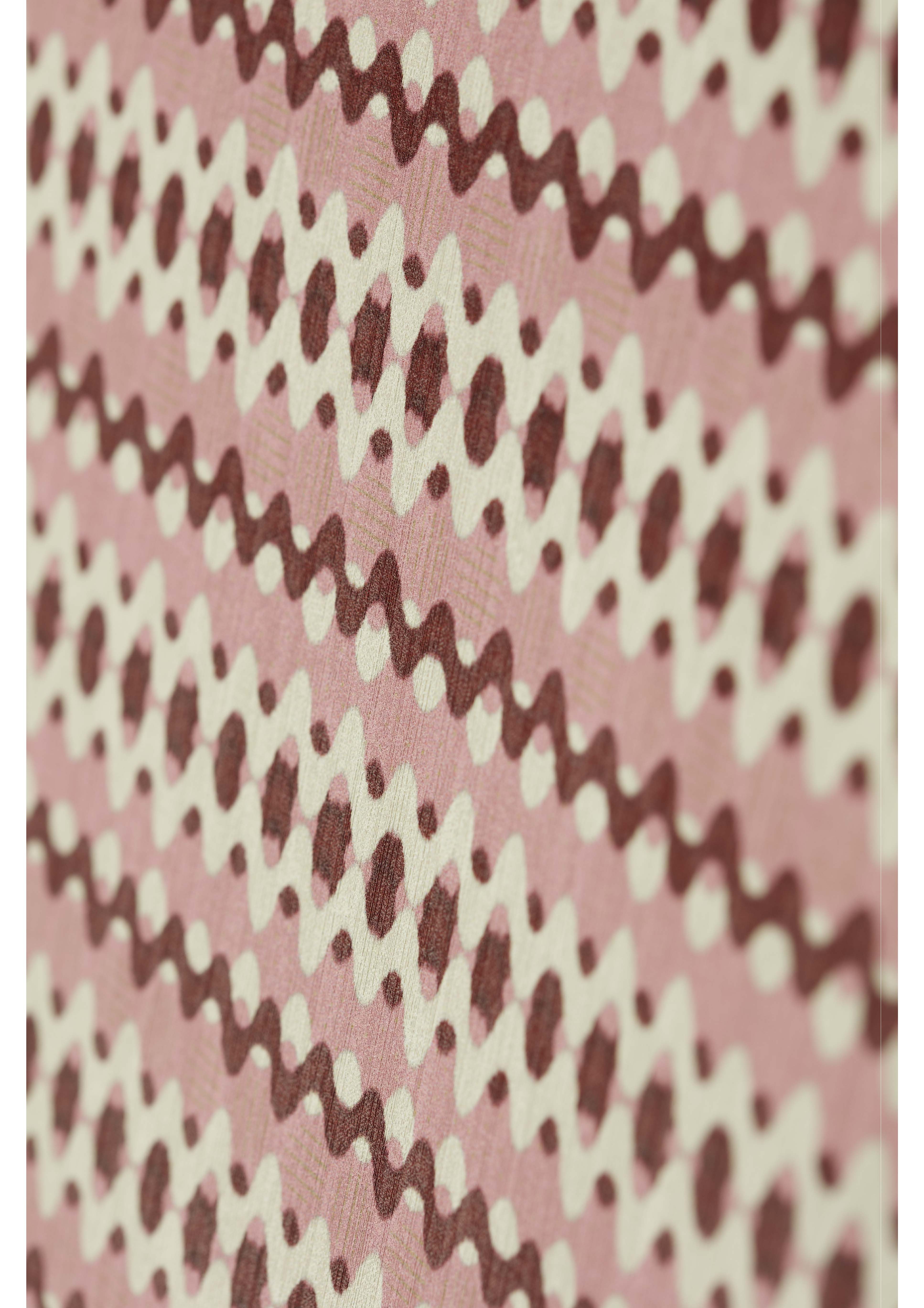 A close-up view of a fabric featuring a zigzag pattern in shades of pink and cream, with dots interspersed throughout the design. The fabric displays a textured appearance, enhancing the visual interest of the pattern.