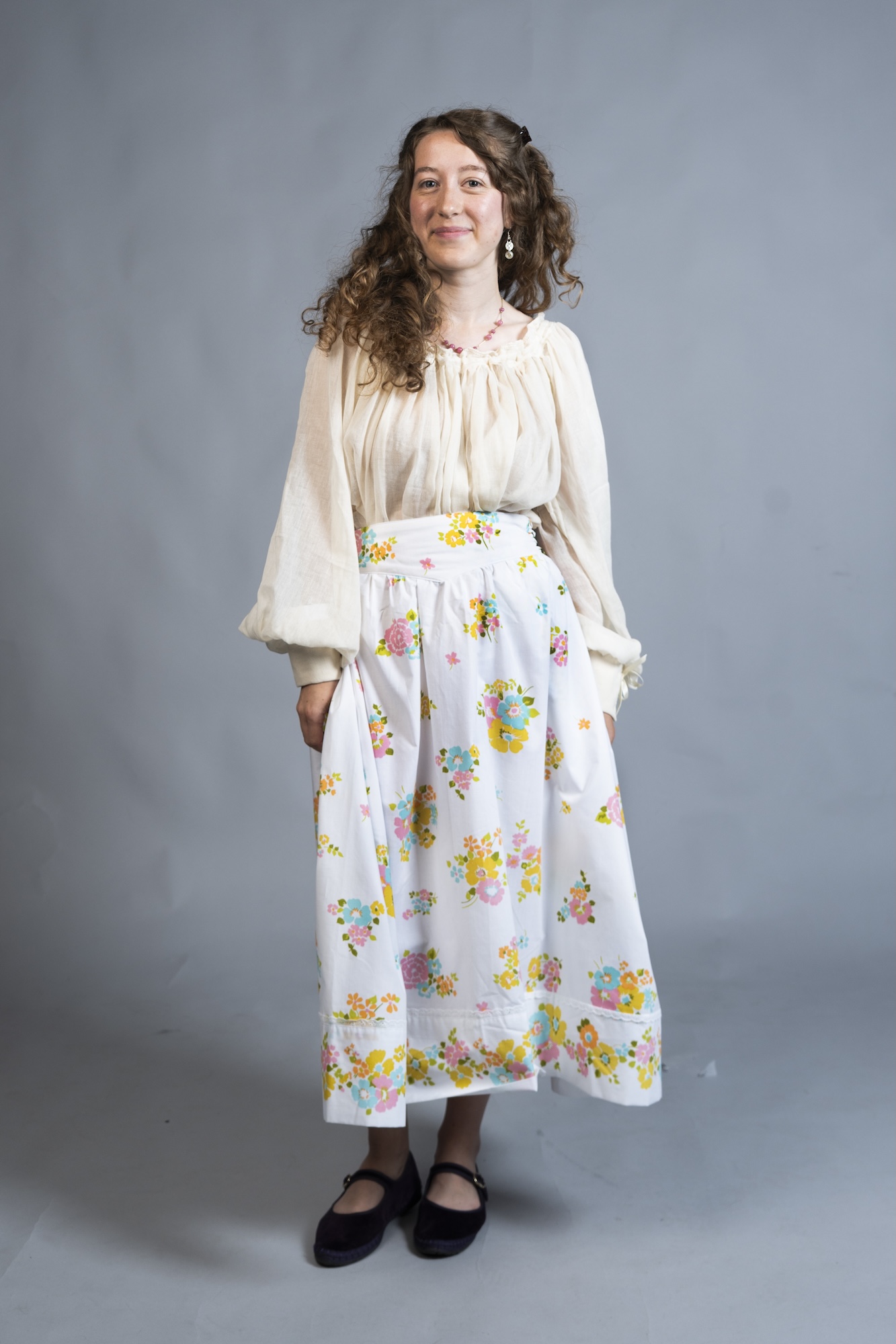 A model stands against a plain grey studio backdrop, with black shoes.