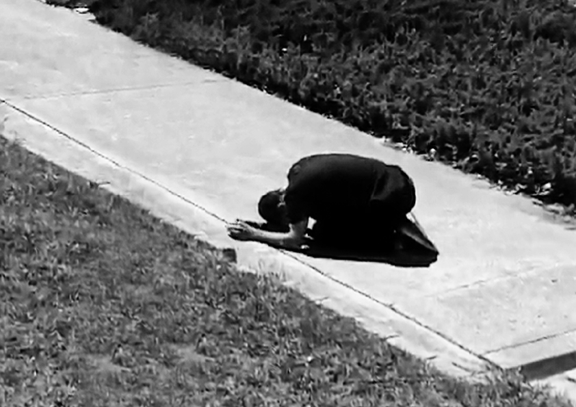 Black and white photograph of ban curled up in a ball on a path