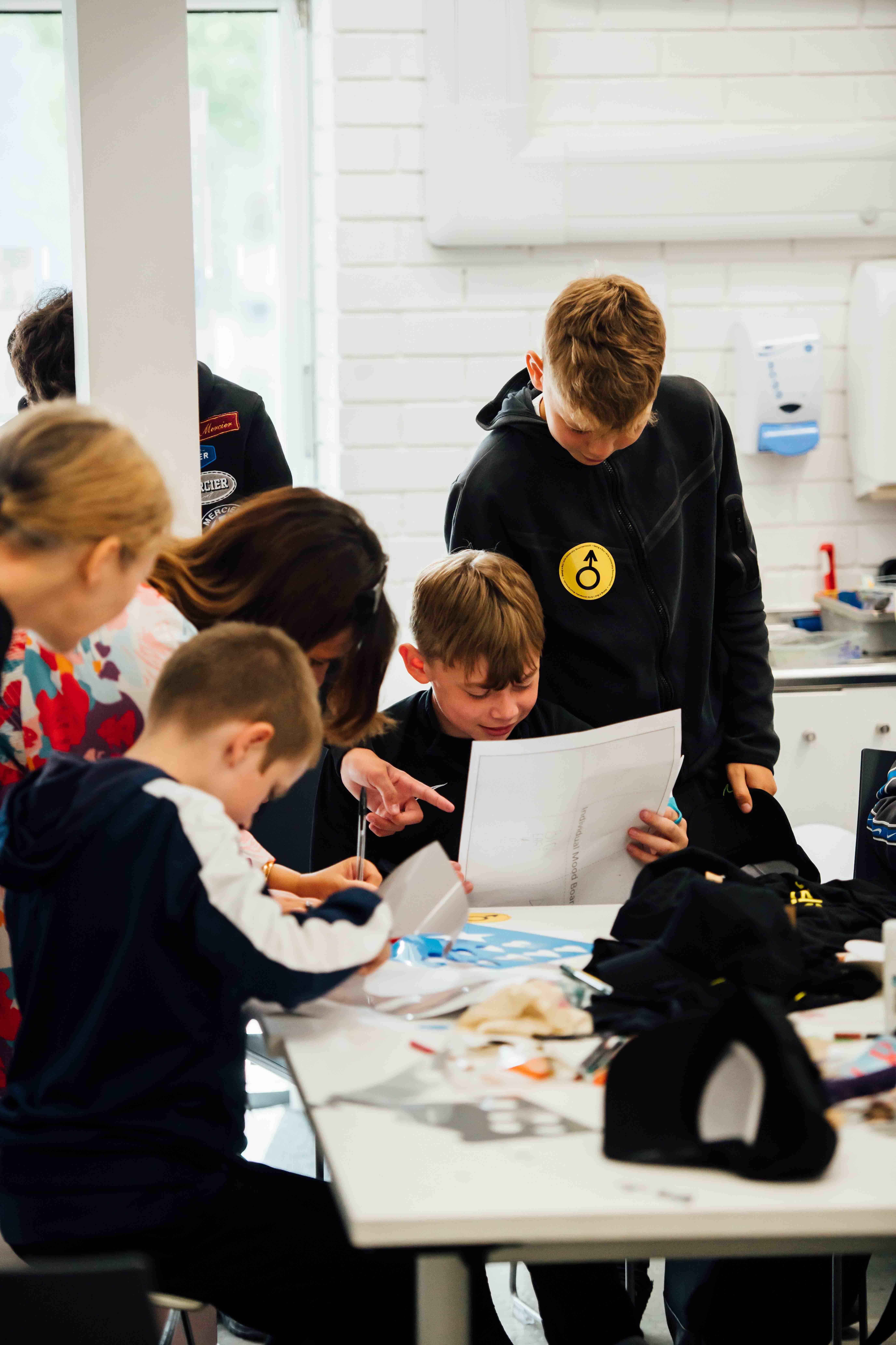 Four boys and two staff members gathered around a studio desk looking at their work.