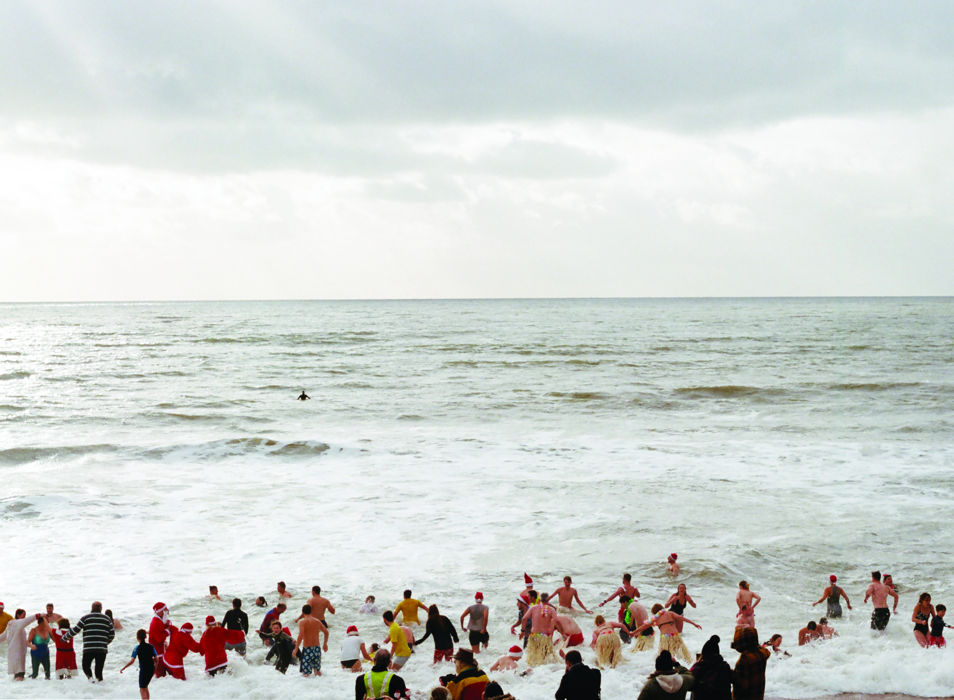 People dressed up as santa running into the sea