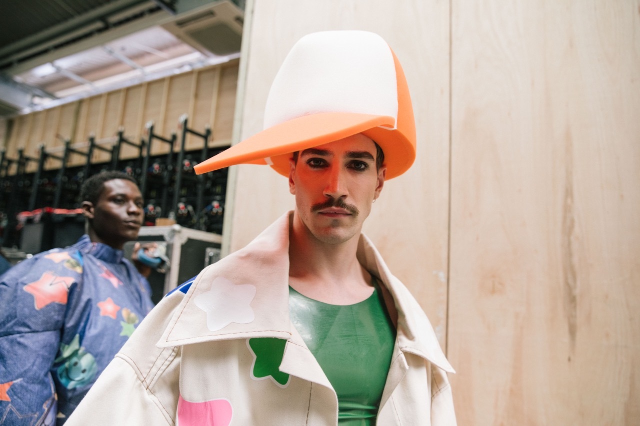 A student model wearing an oversized orange hat