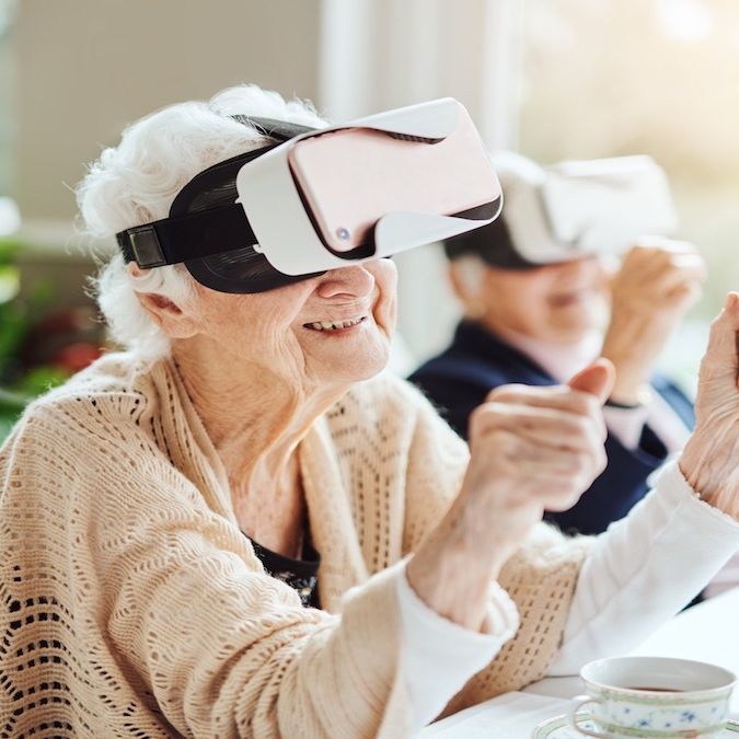 A carer is helping an elderly resident use a VR headset