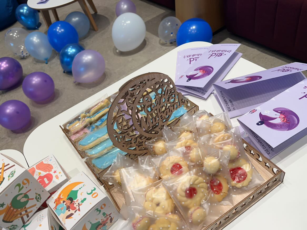 A selection of sweets in plastic wrap, boxes and leaflets on a table, and balloons in the background.