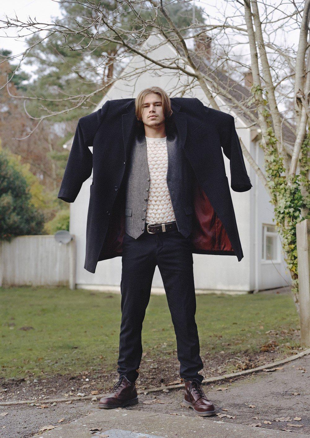 Man in field holding a coat