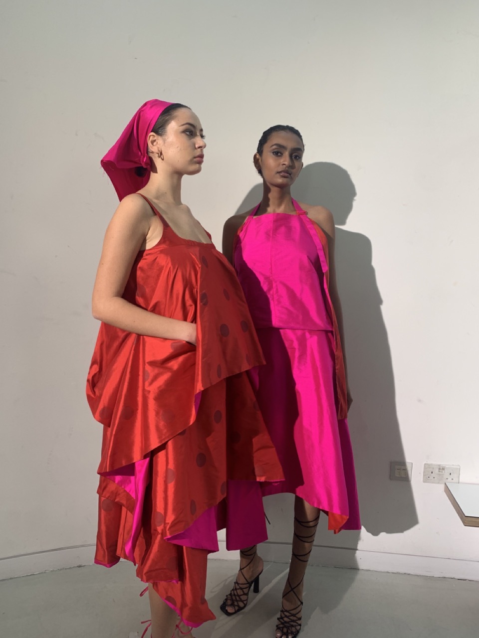 Students dressed for Graduate Fashion Week 2023 in pink and red dresses