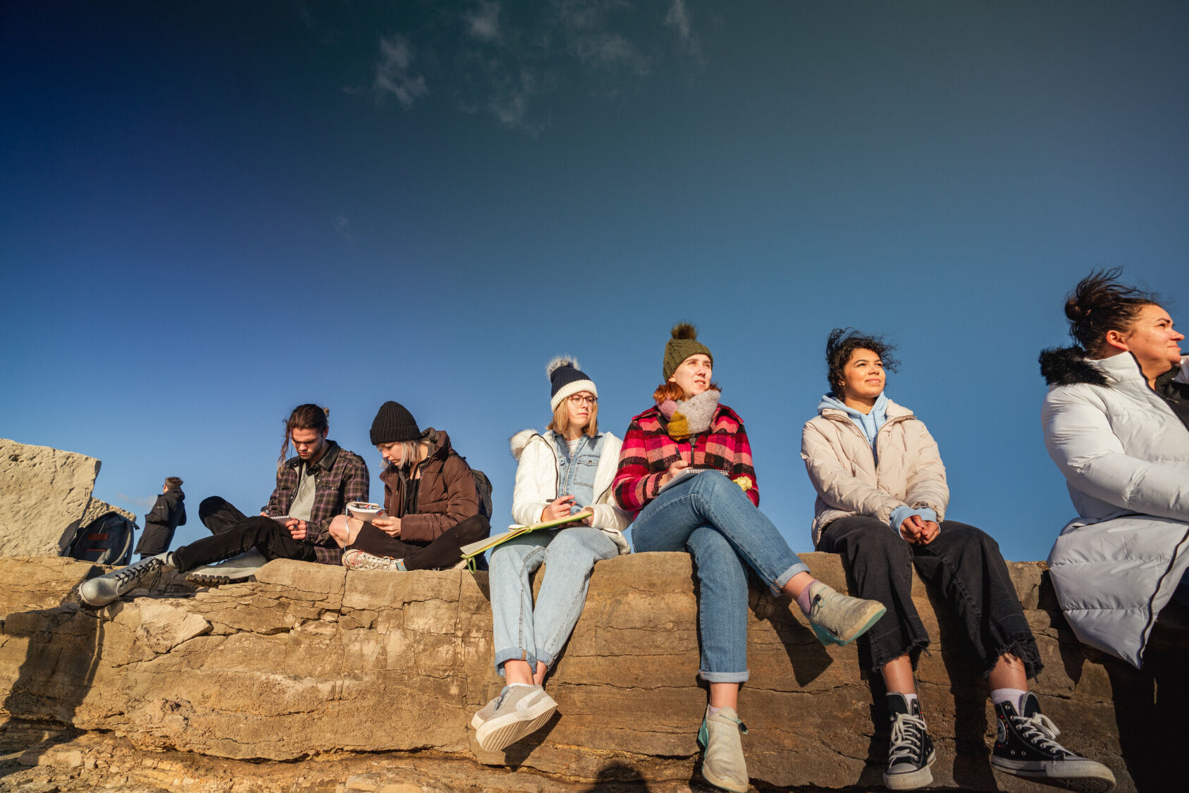 A group of creative writing students sat on a rocky outcrop.