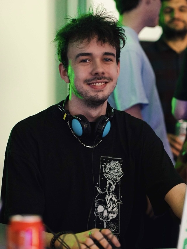 Zac De Saulles wearing headphones and a black t-shirt, sat at a computer.