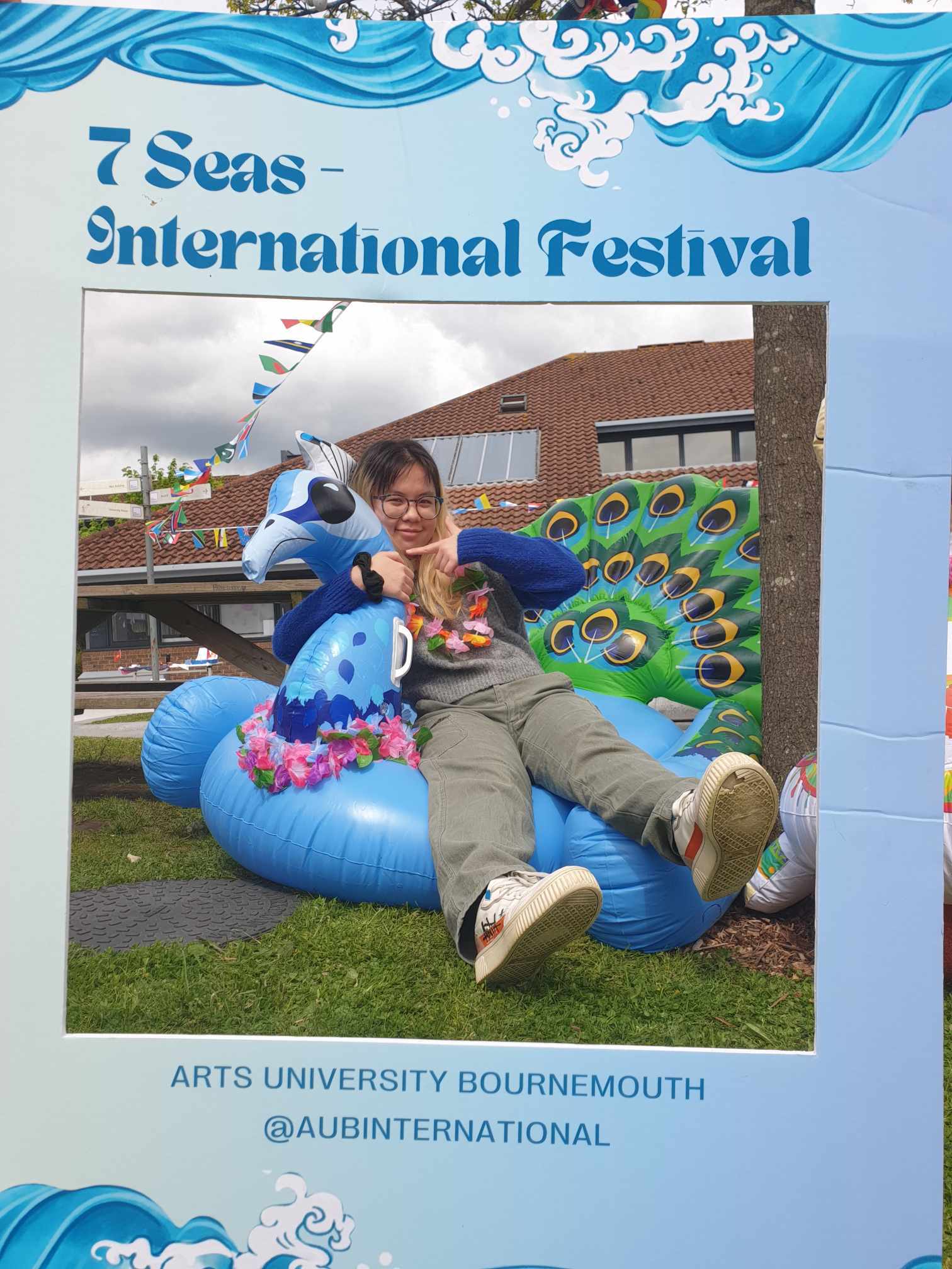 Ngan Nguyen in a blue 7 Seas International Festival frame in AUB courtyard on a peacock inflatable seat.