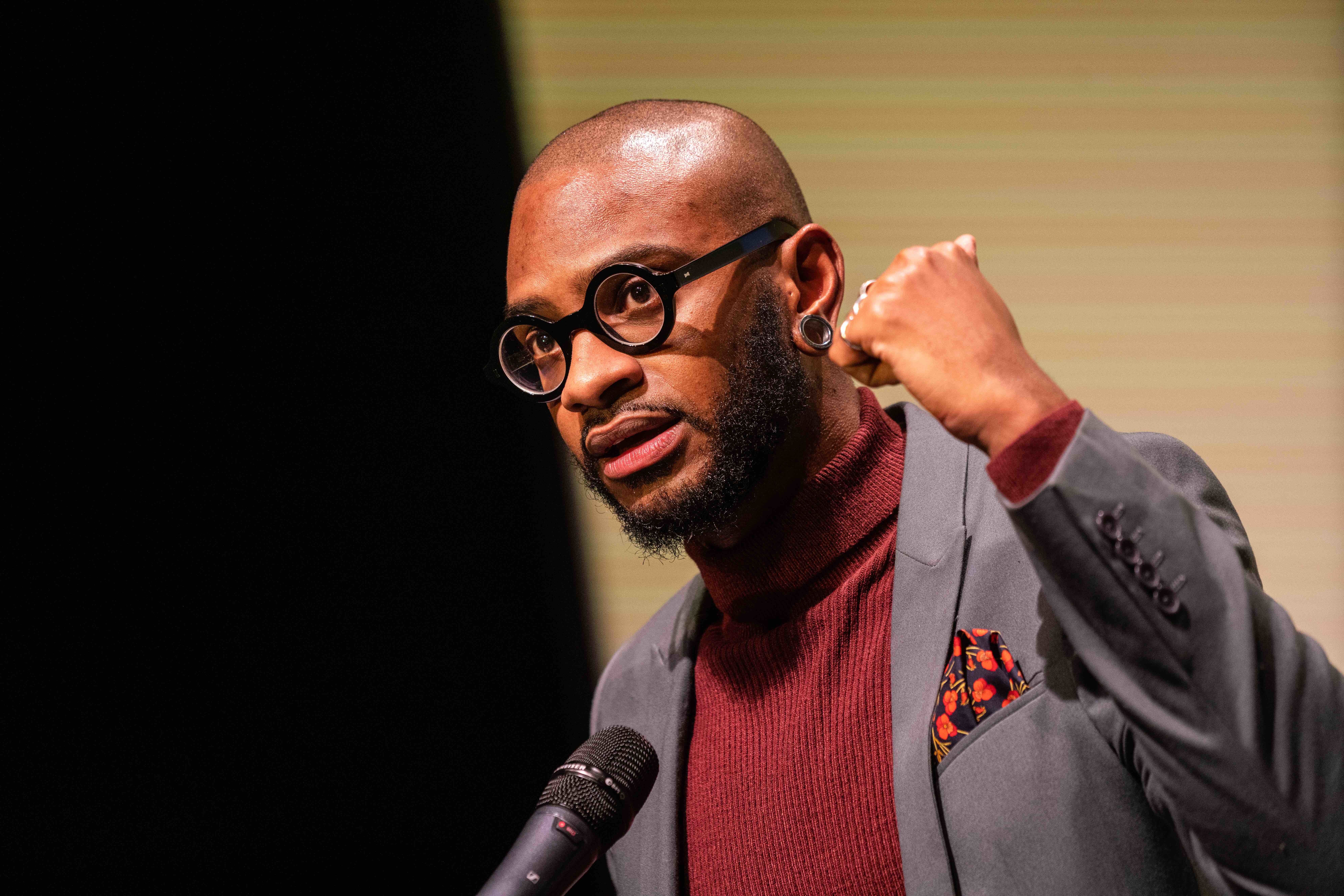 A person raises a fist while speaking into a microphone.