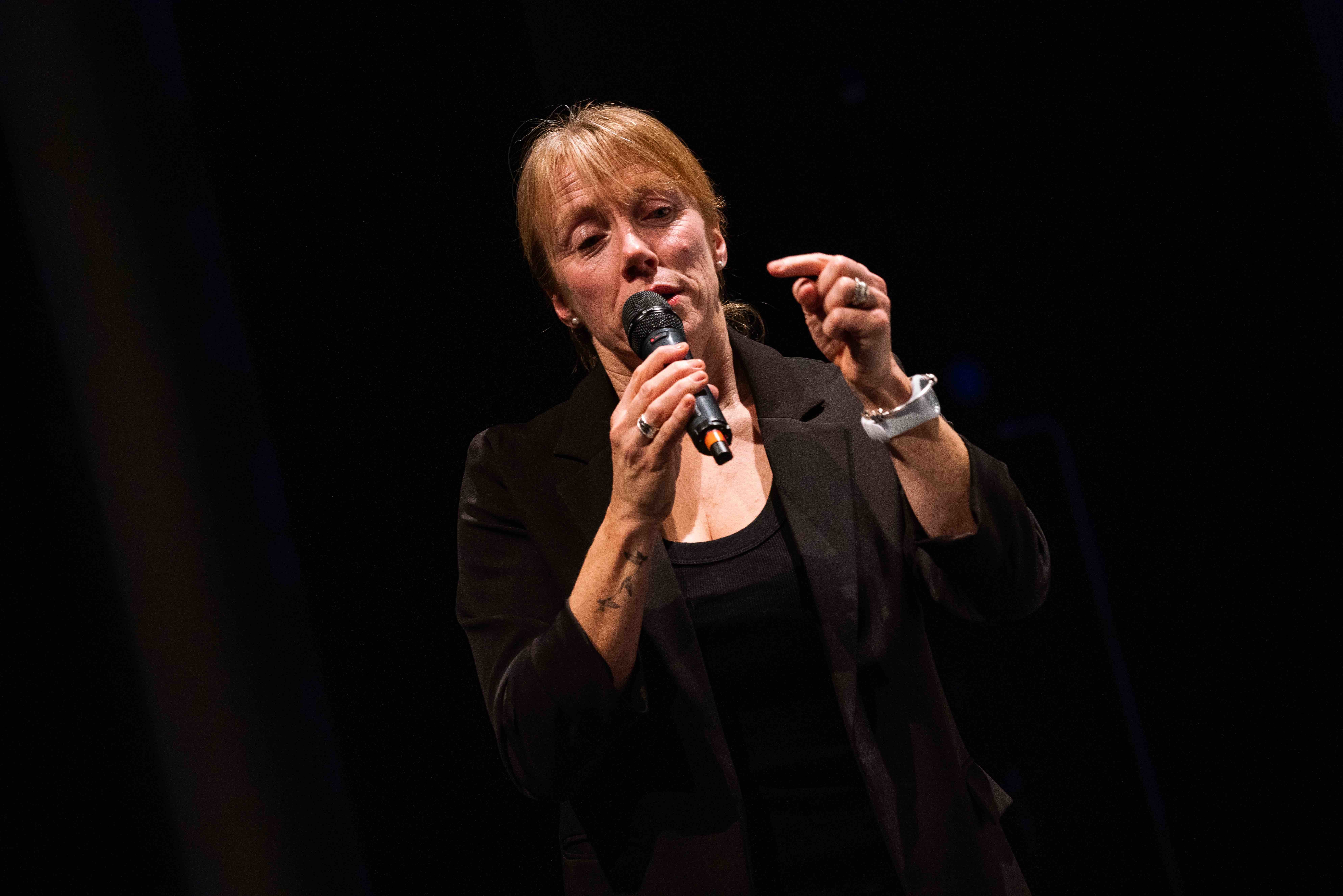 A person speaks into a microphone that they are holding up to their face.