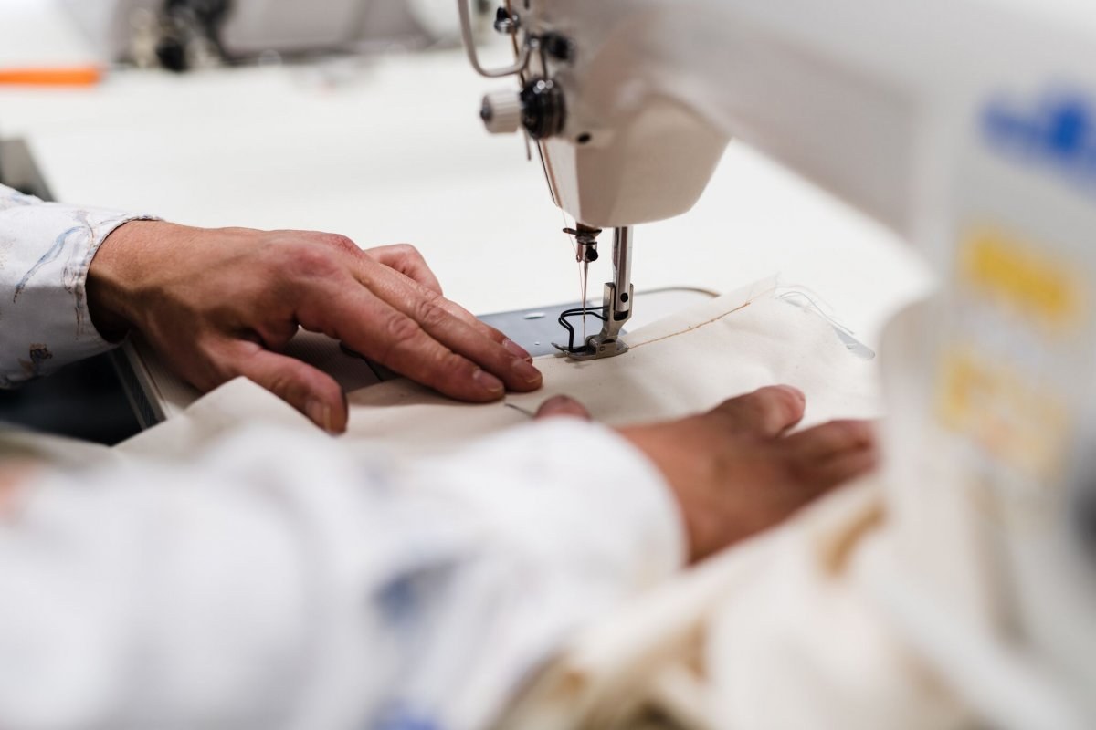 Close up of a pair of hands feeding fabric through a sewing machine