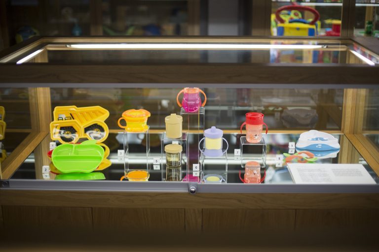 Several plastic objects on display inside a glass museum exhibition cabinet.