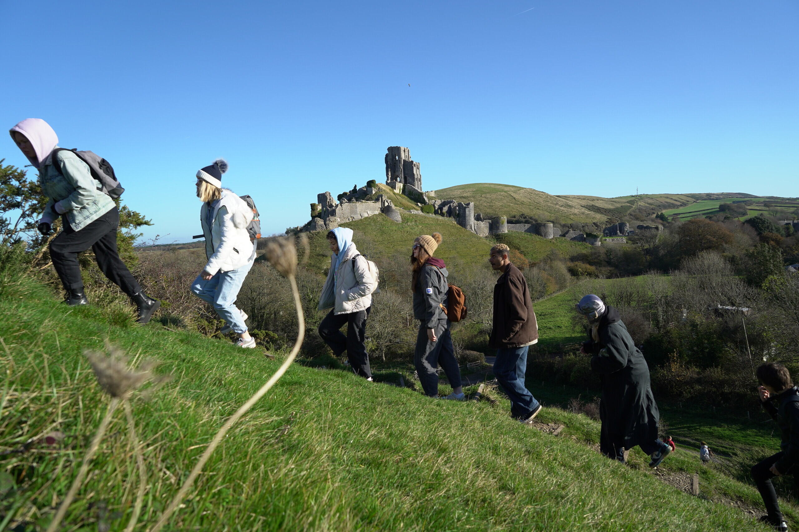 Creative Writing students walking up a hill with Corfe Castle in the background.