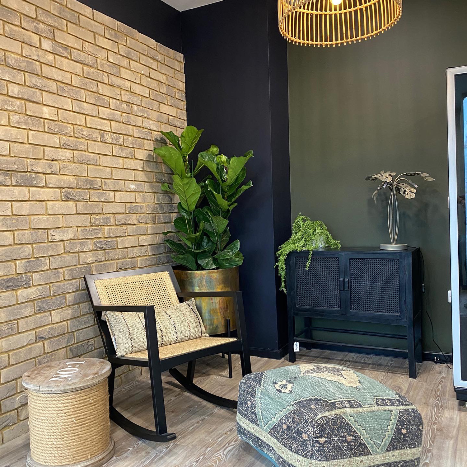A corner with a chair, furniture, plants and lighting.