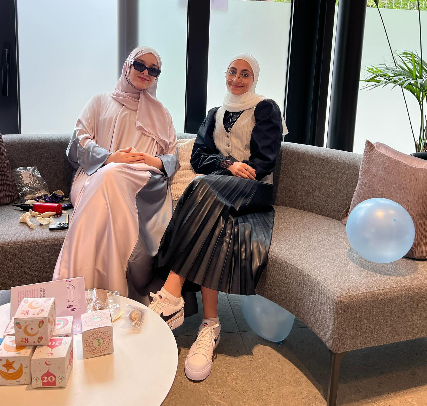 Two AUB students sitting on a curved sofa, attending the Eid el-Fitr celebration event at AUB.