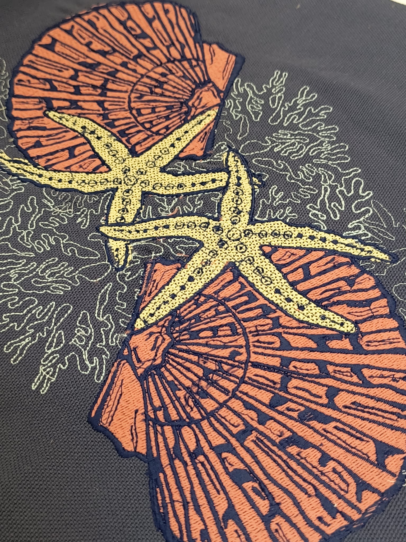 Orange and navy scallop shells with yellow starfish illustration on dark grey background, white coral outlines surrounding composition.
