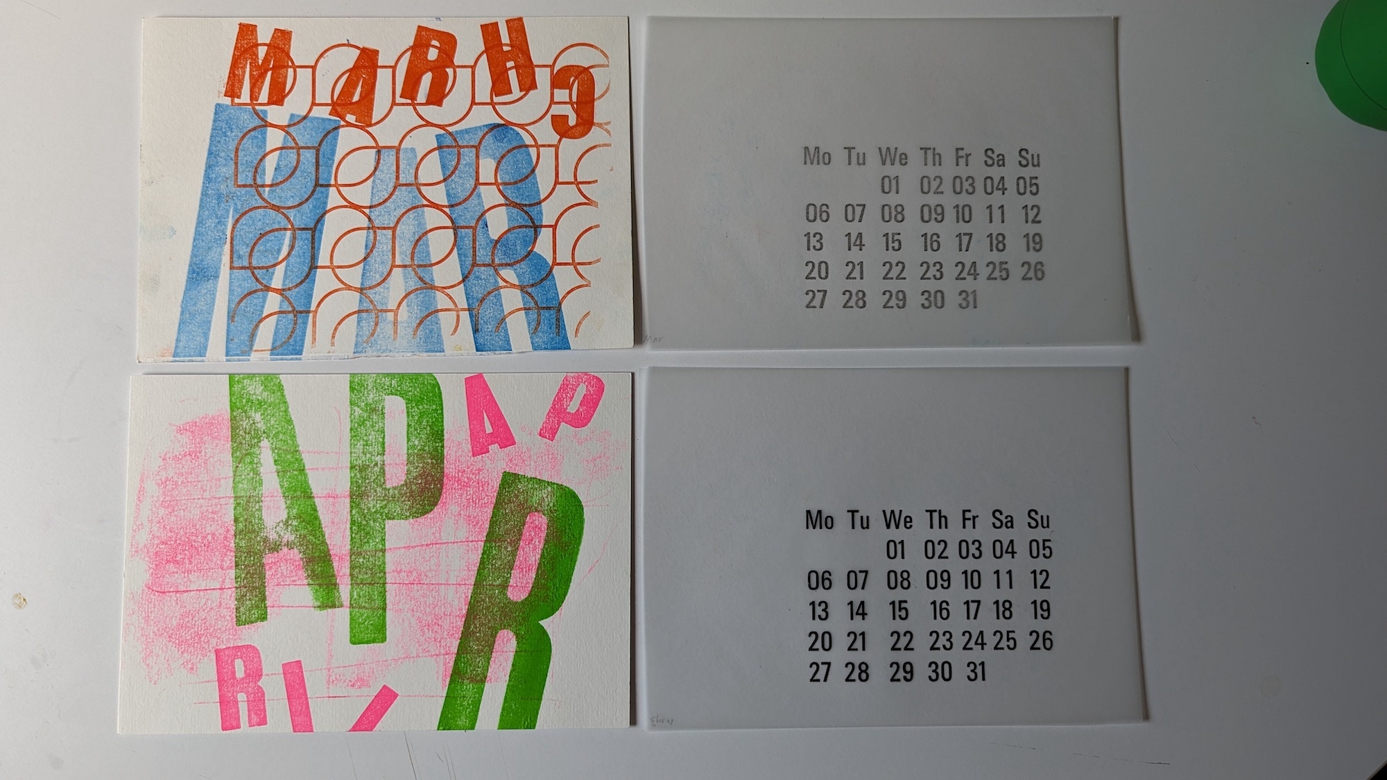 Colourful blue, orange, green and pink graphics and calendar, text reads 'MARC3, MAR, ARP' on four pieces of paper, white background.