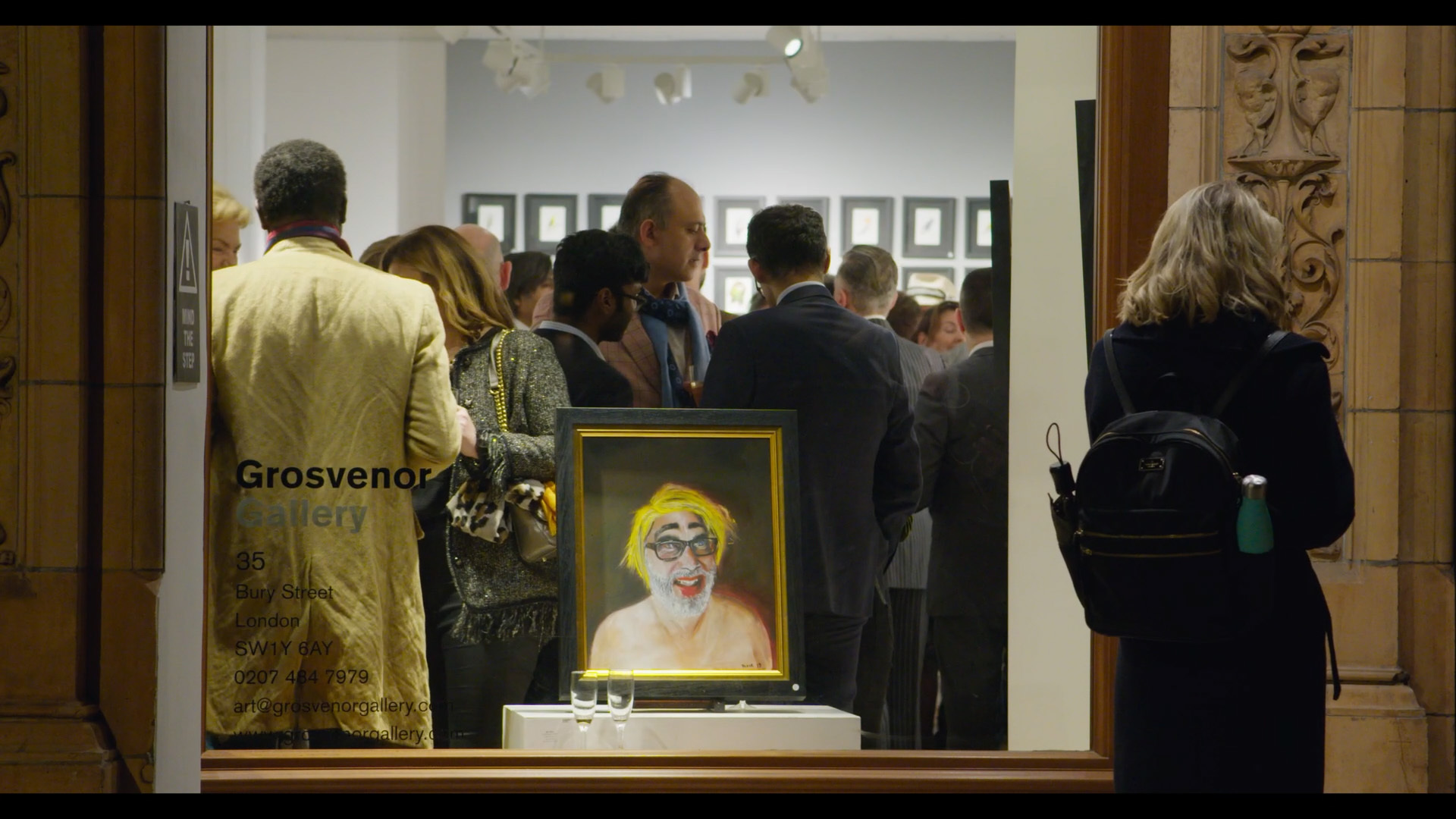 standing outside, looking in through the window of a busy Grosvenor Gallery private view