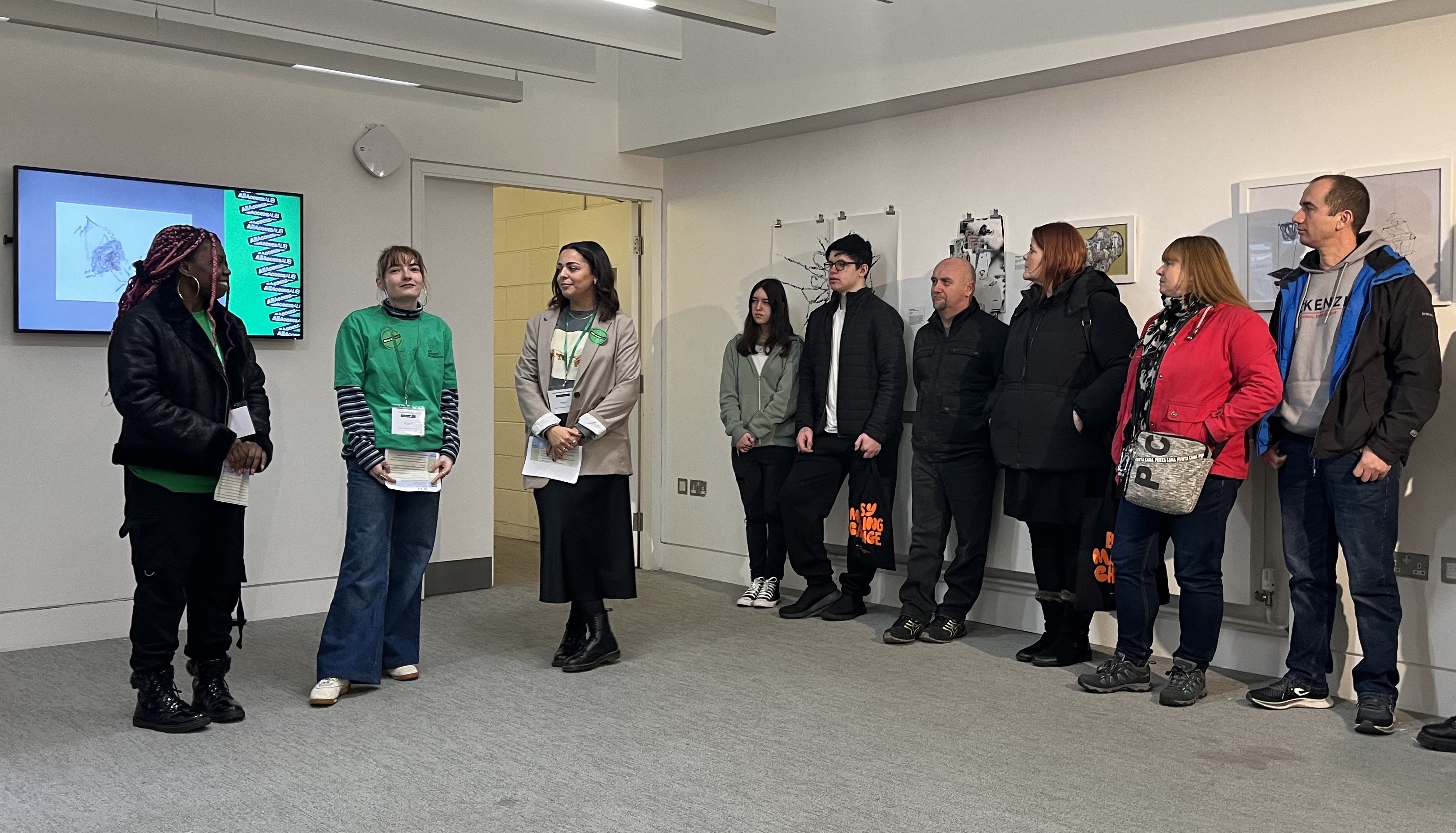 A member of AUB staff and two Outreach Ambassadors giving a presentation to a group of people lined up opposite them in TheGallery, AUB Campus.