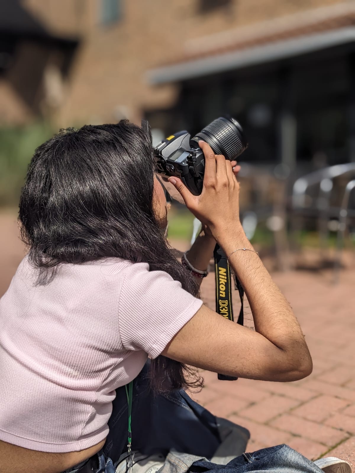 A close up of a student using a digital camera to take a photo of a building above them