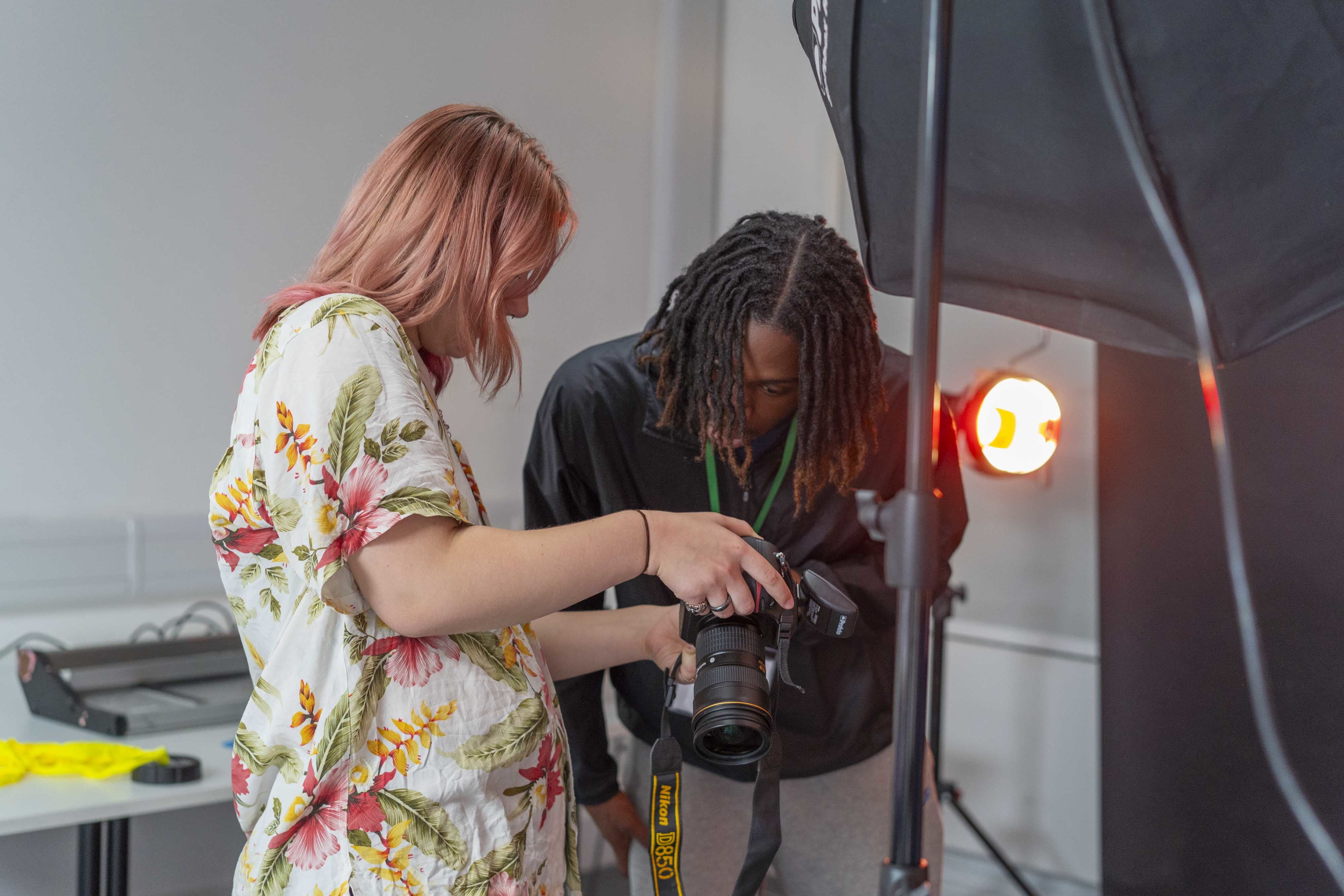 An All Access AUB student holding a camera to be examined by a member of staff.