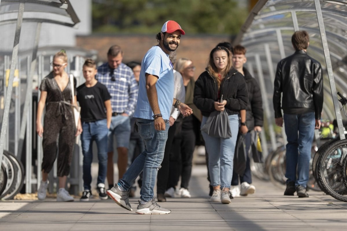 Crowd of people walking on a path between two sets of bike sheds.
