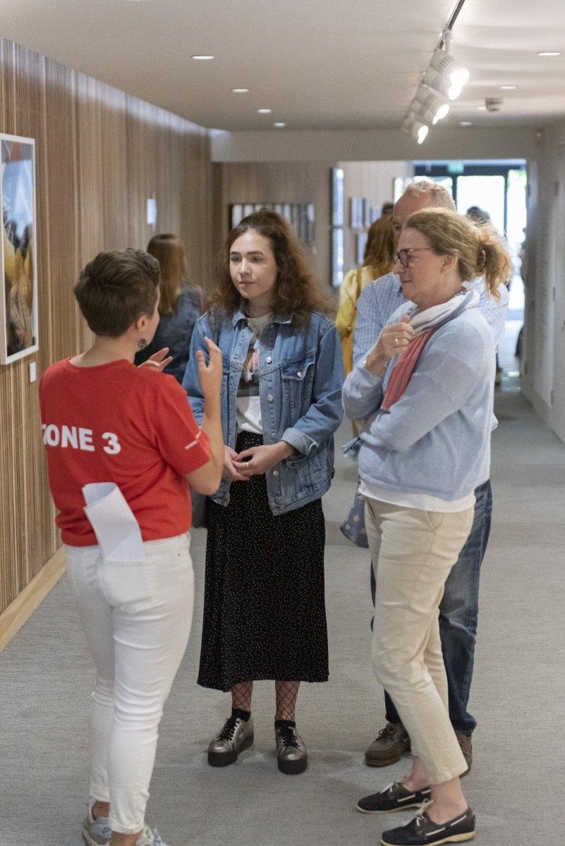 Student ambassador speaks with a family of three people in a corridor.