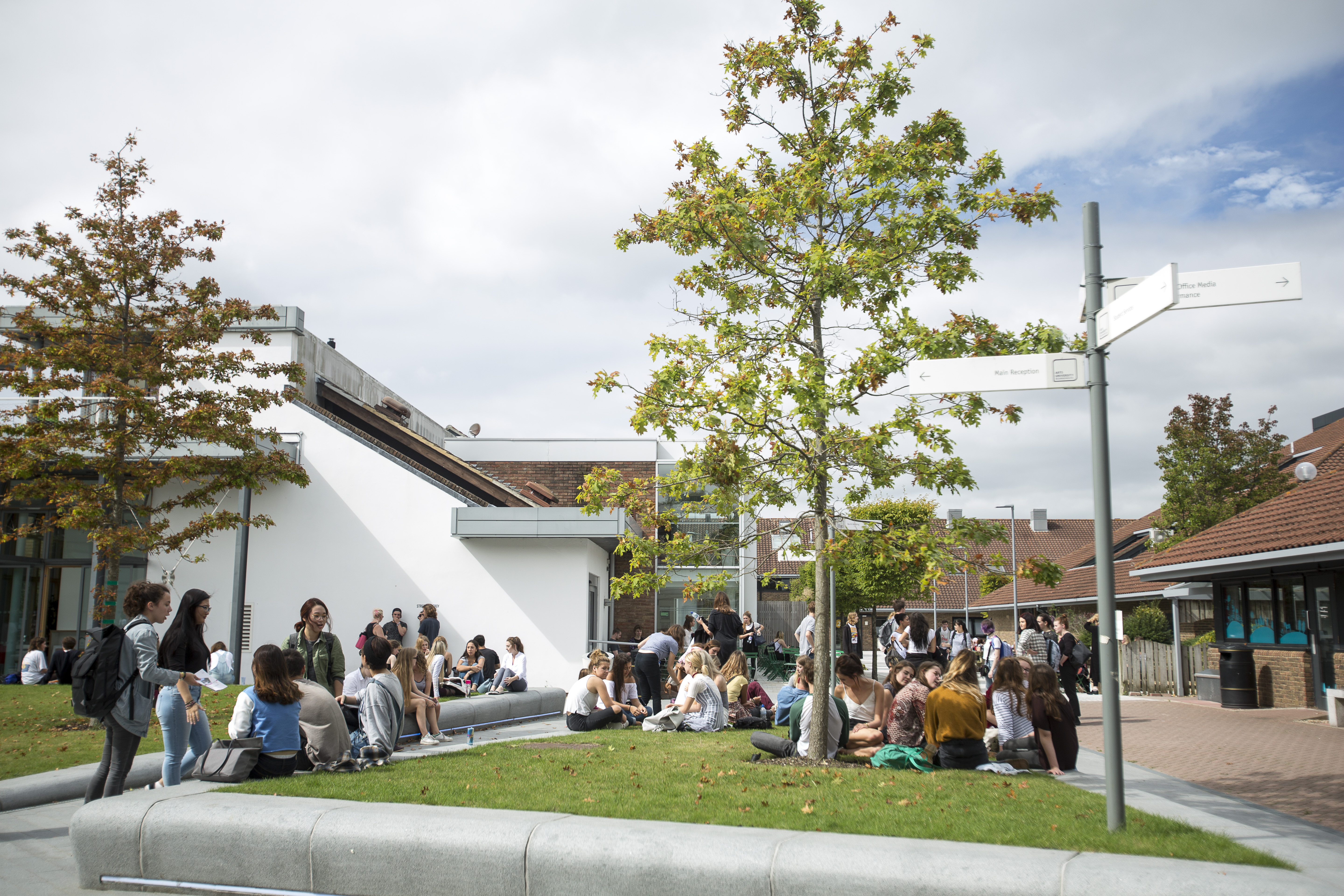Groups of people gathering on a university campus courtyard and sitting on lawns.