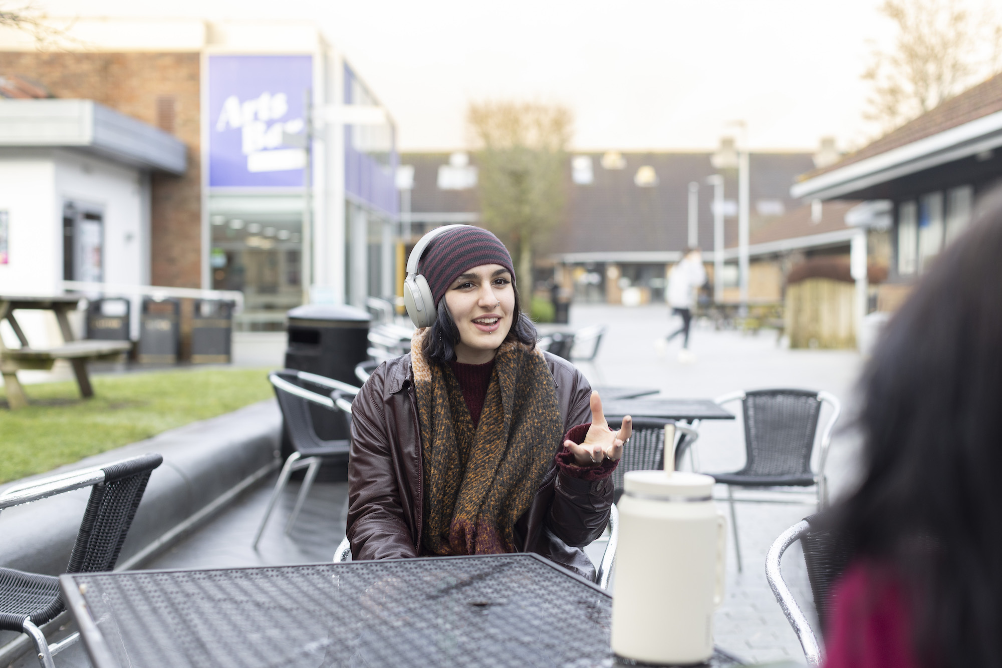 A student chats to another student while sitting at a table in the courtyard on AUB Campus.