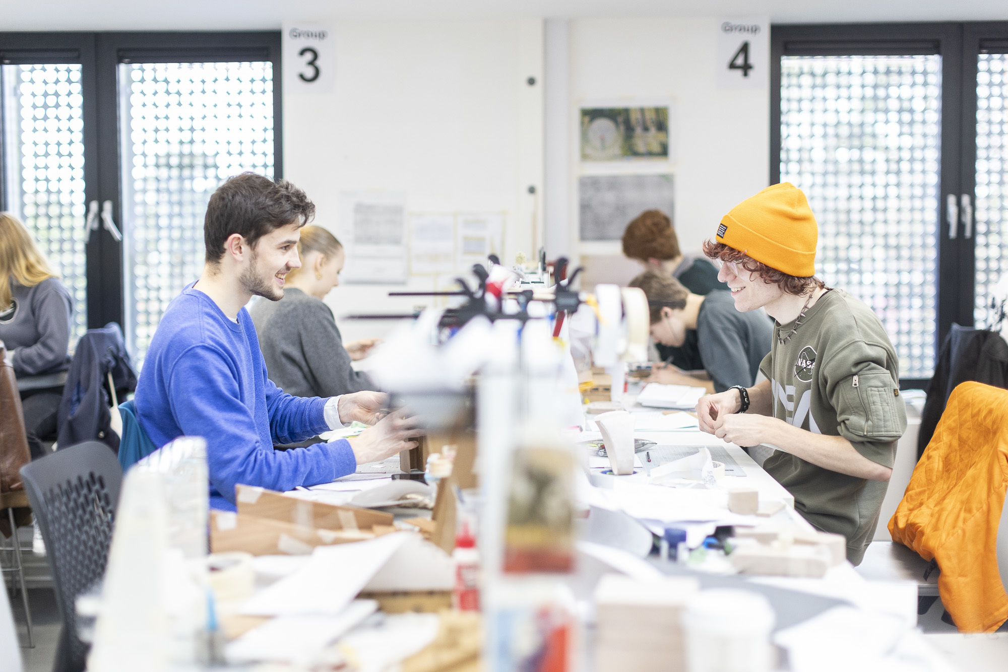 Two AUB students sitting opposite each other and smiling working in a studio.