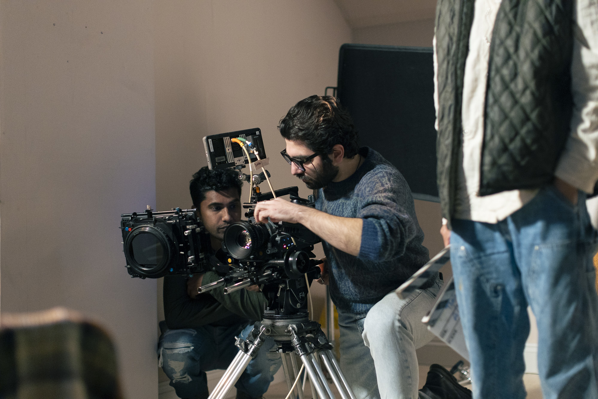 A BA (Hons) Film Production student setting up a camera on an indoor film shoot. Other crew members are visible in the foreground and background.