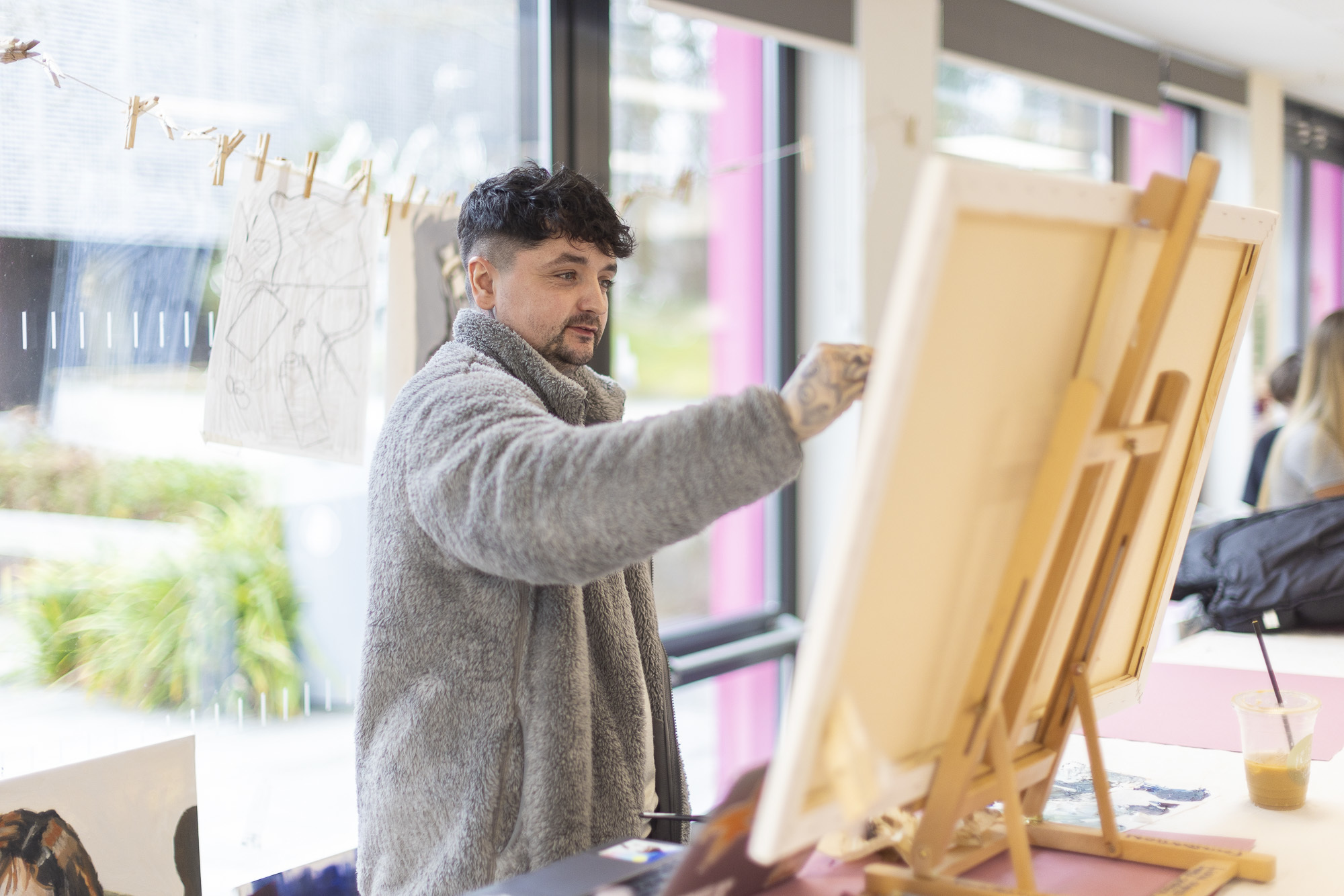 An Arts University Bournemouth student painting on a canvas in front of them in a studio space.