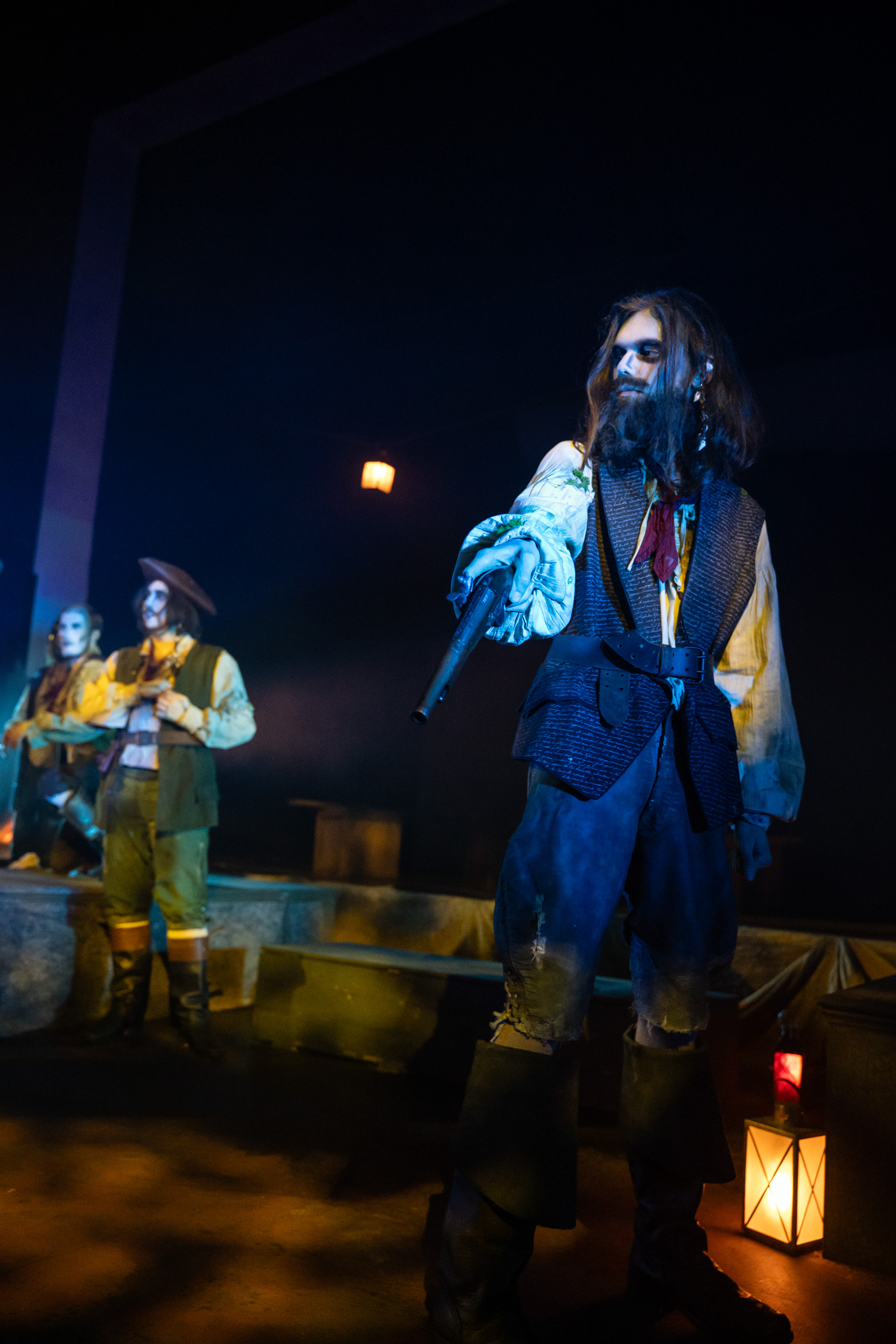 A BA (Hons) Acting student in period costume and ghostly makeup onstage in a performance of "Moonfleet", pointing a pistol down off-camera.