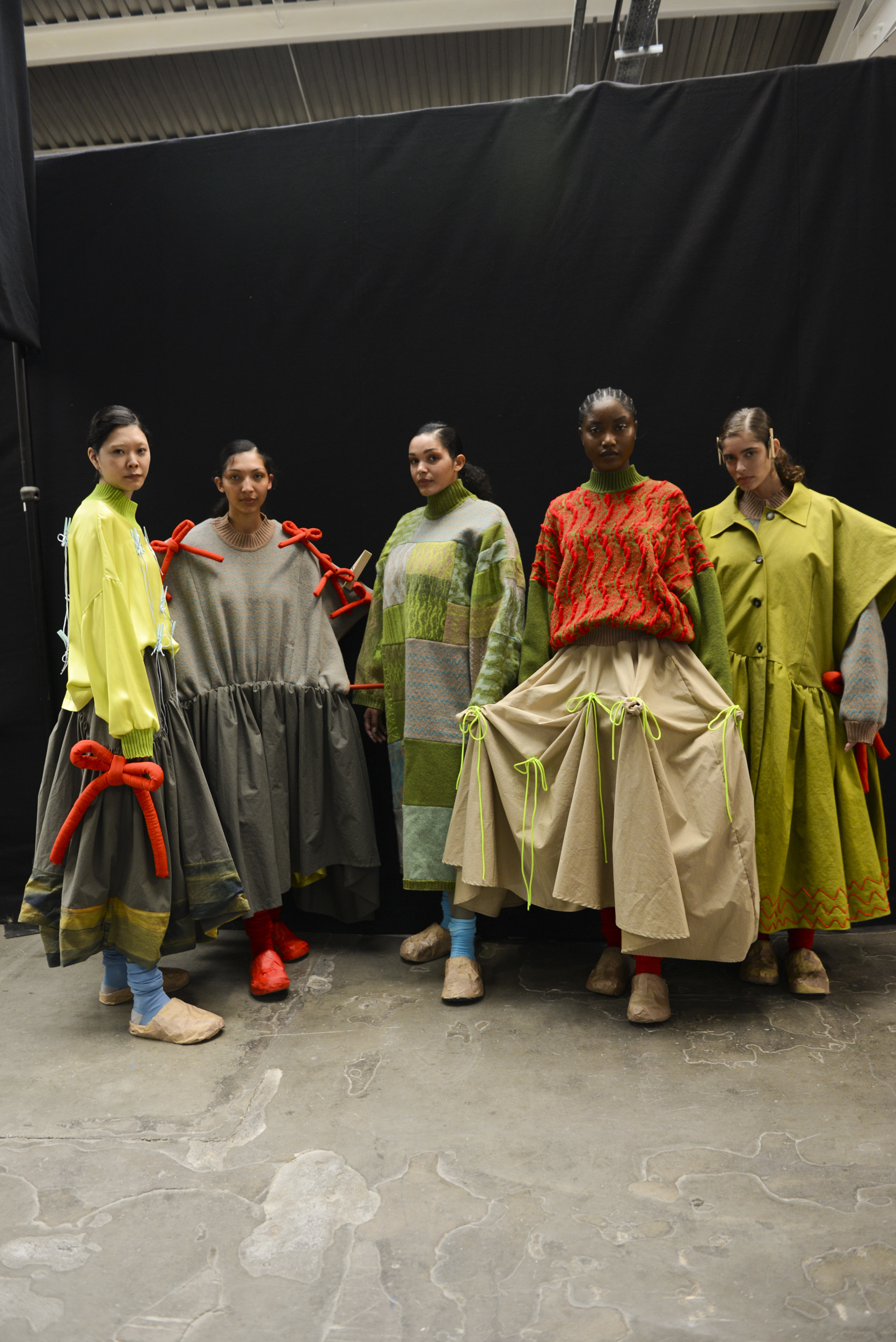 Five models lined up backstage at Graduate Fashion Week 2024 wearing creations by a BA (Hons) Fashion student.