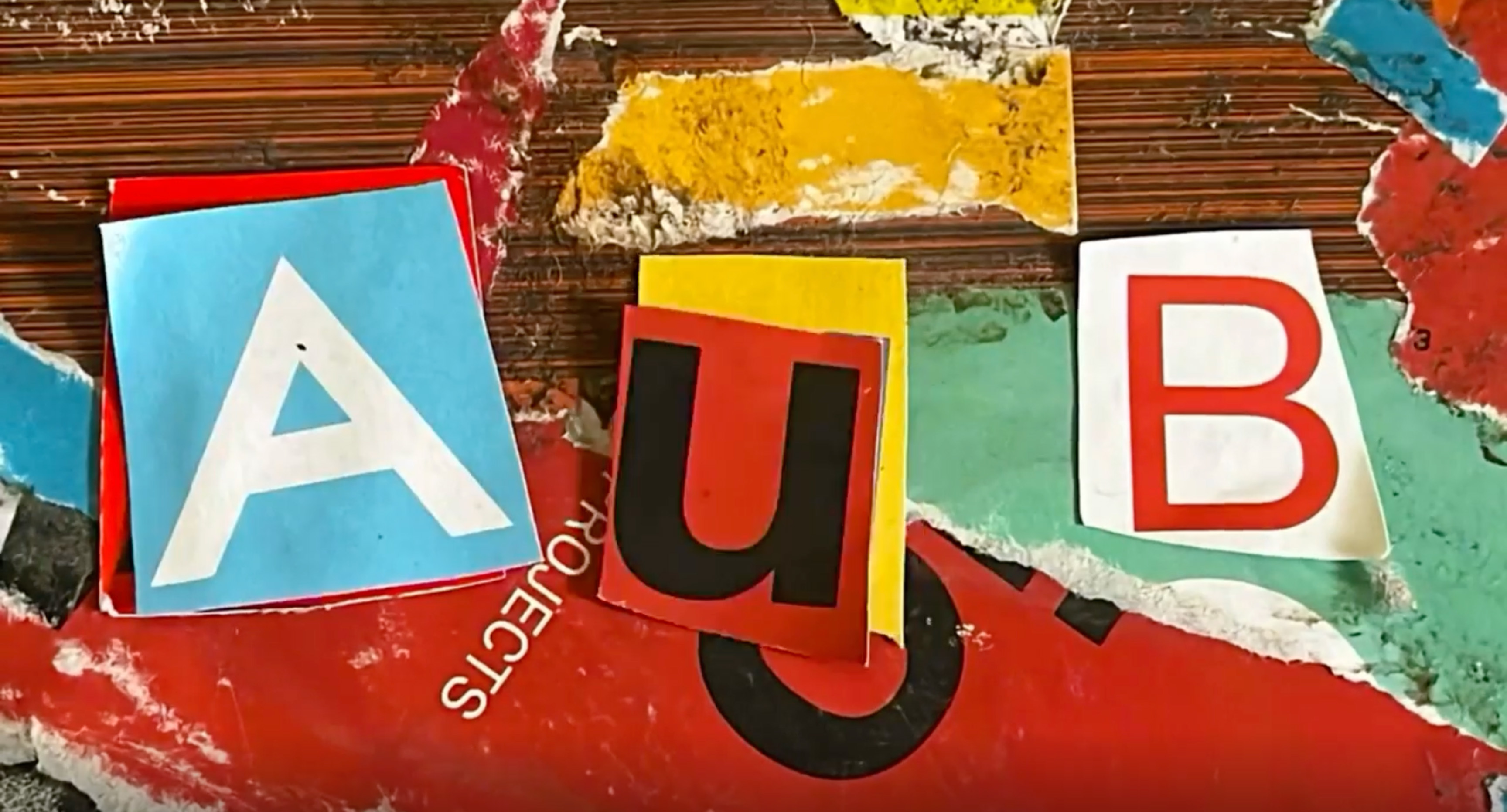 The letters AUB arranged in a collage style with different cut-out pieces of card or paper on a messy background.