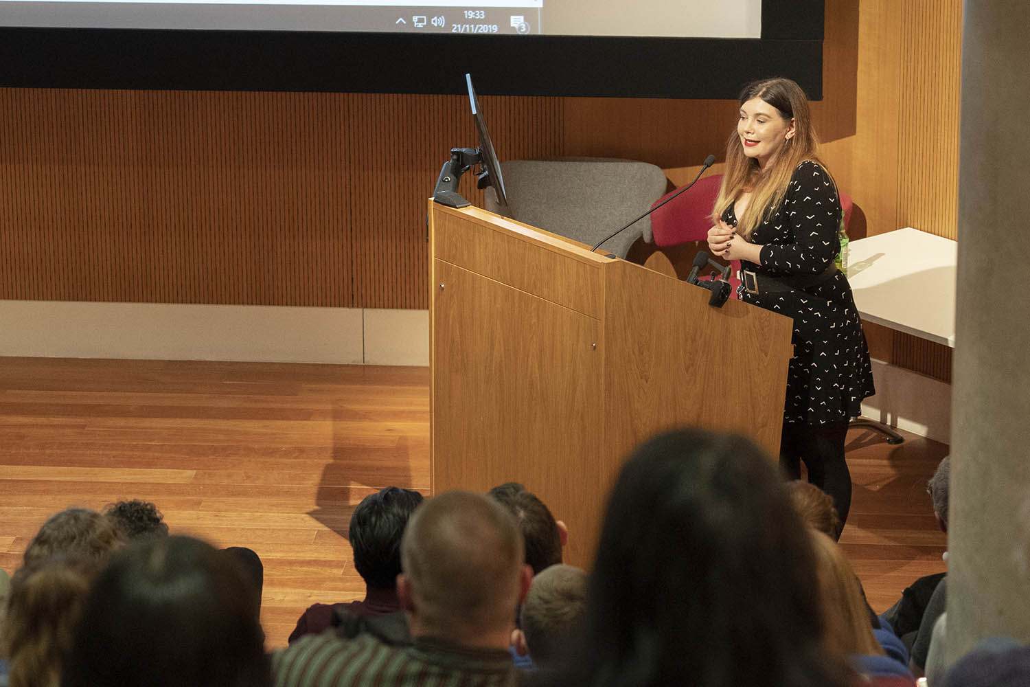 R Dibiaso standing at a lectern in a lecture theatre in front of an audience.