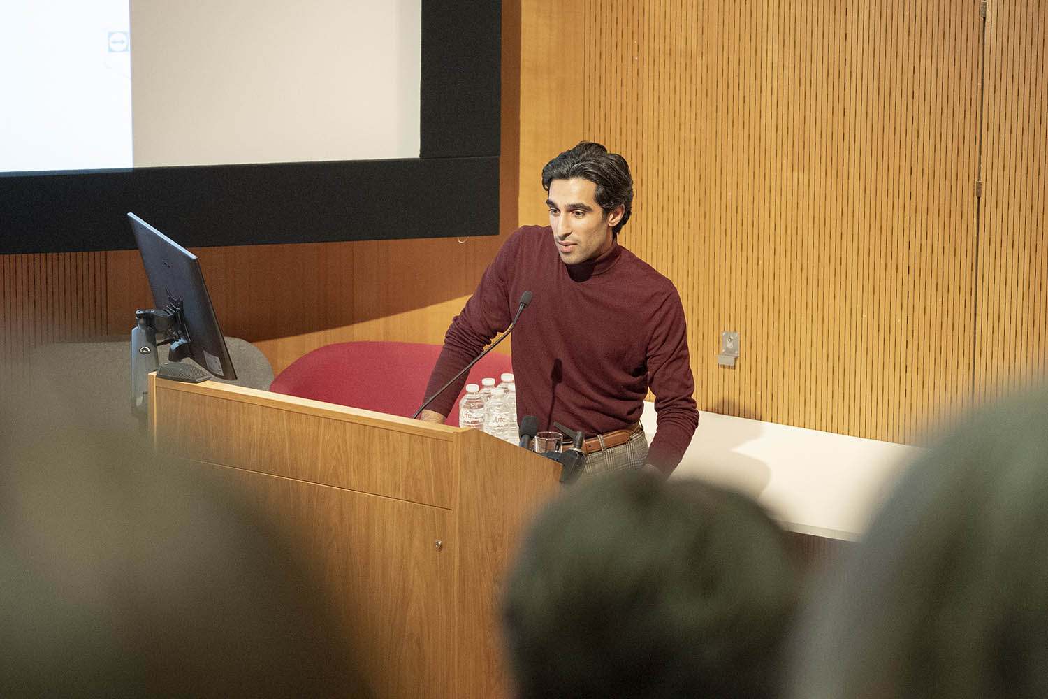 N Jamali standing at a lectern and giving a presentation in a lecture theatre.