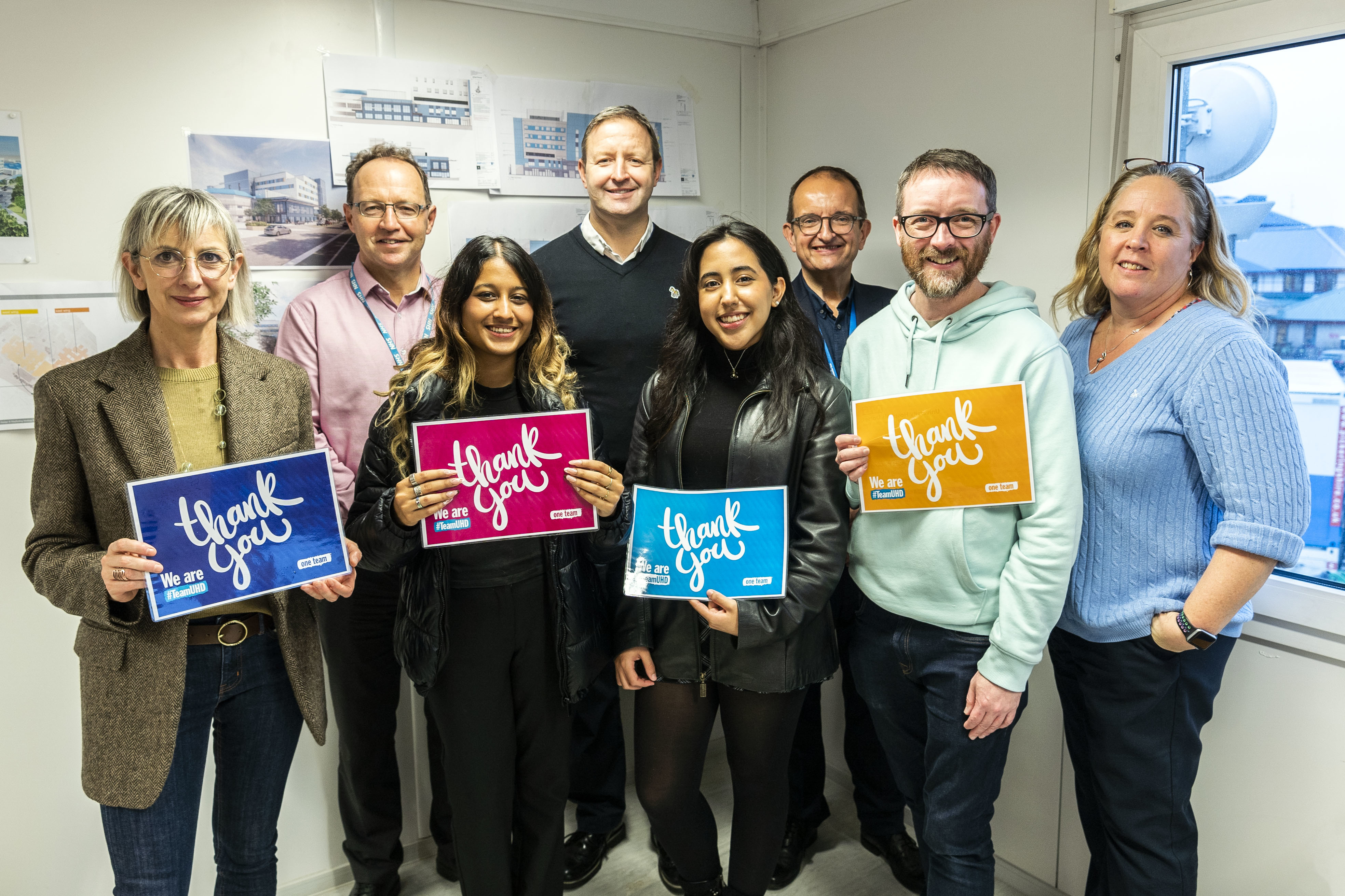 AUB students and staff were thanked for their design work at Royal Bournemouth Hospital. A group of people poses in a hospital corridor. Four of them are holding certificates.