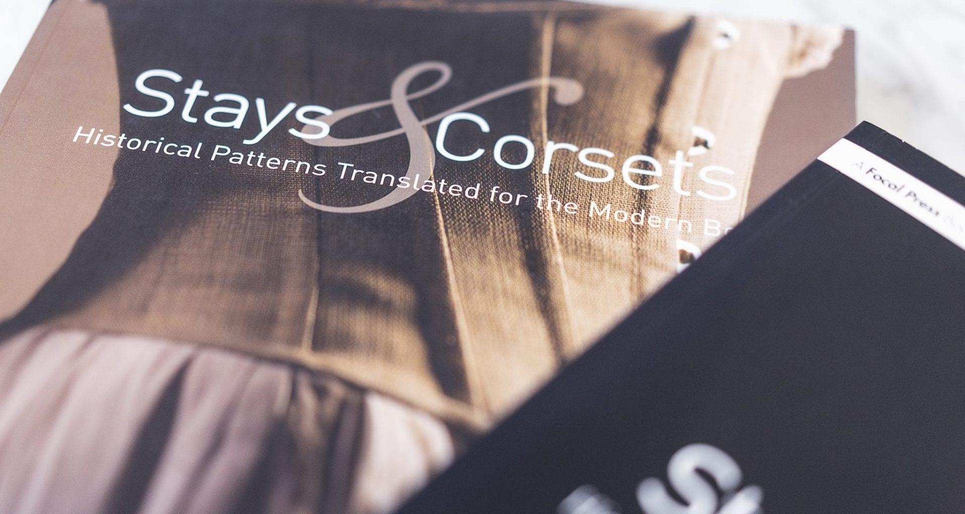 The front cover of a book, showing a close-up of a corset. The title reads Stays and Corsets Historical Patterns Translated for the Modern Day