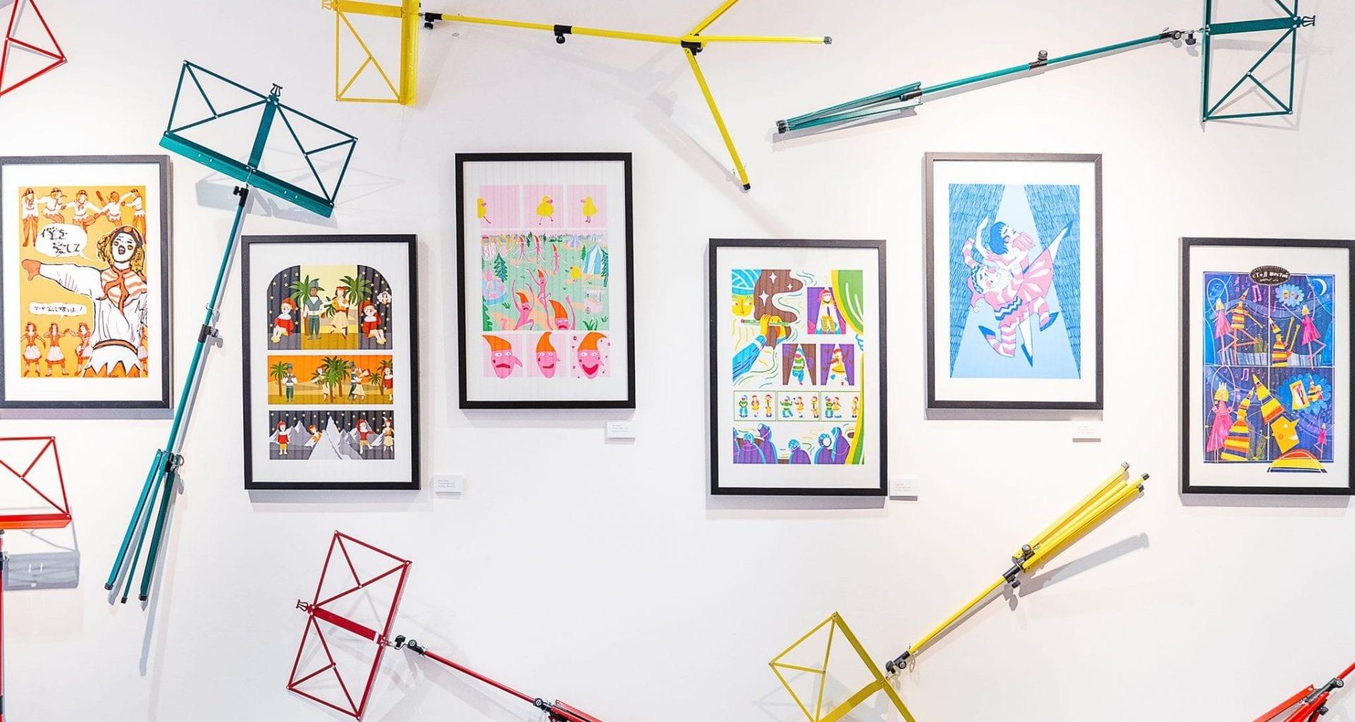 Several framed pictures and music stands hang on a gallery wall