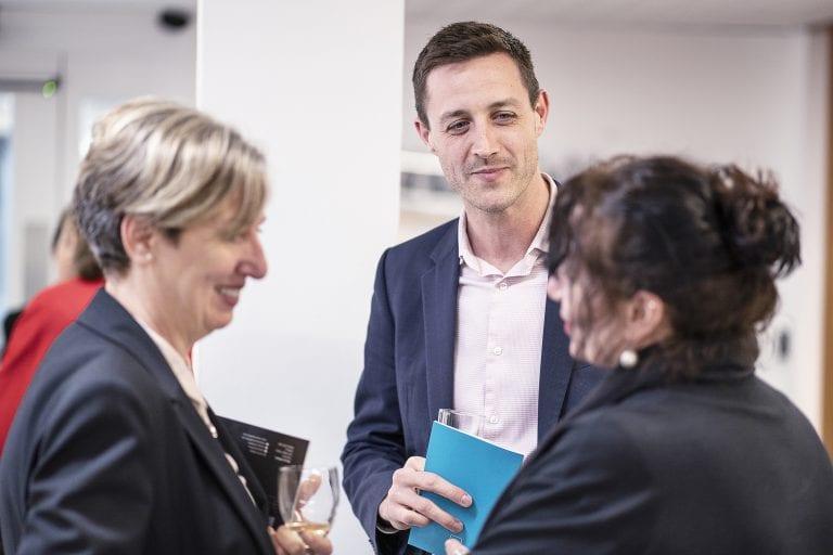 Three people having a conversation in a gallery.