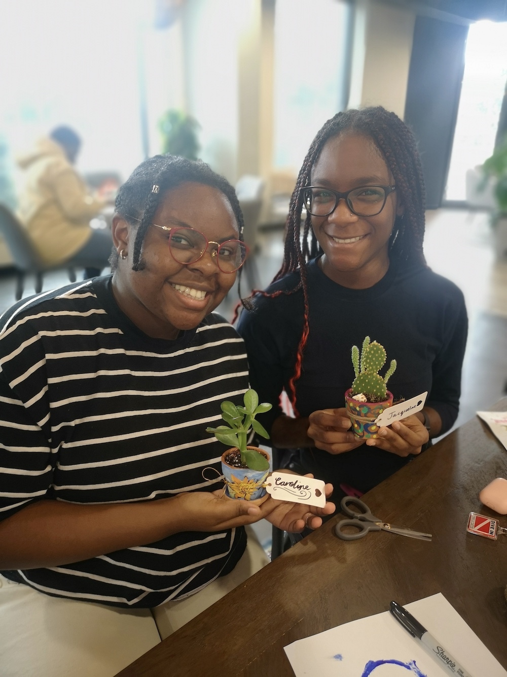 Image of two students presenting their plant pot creations with a cactus in one of them