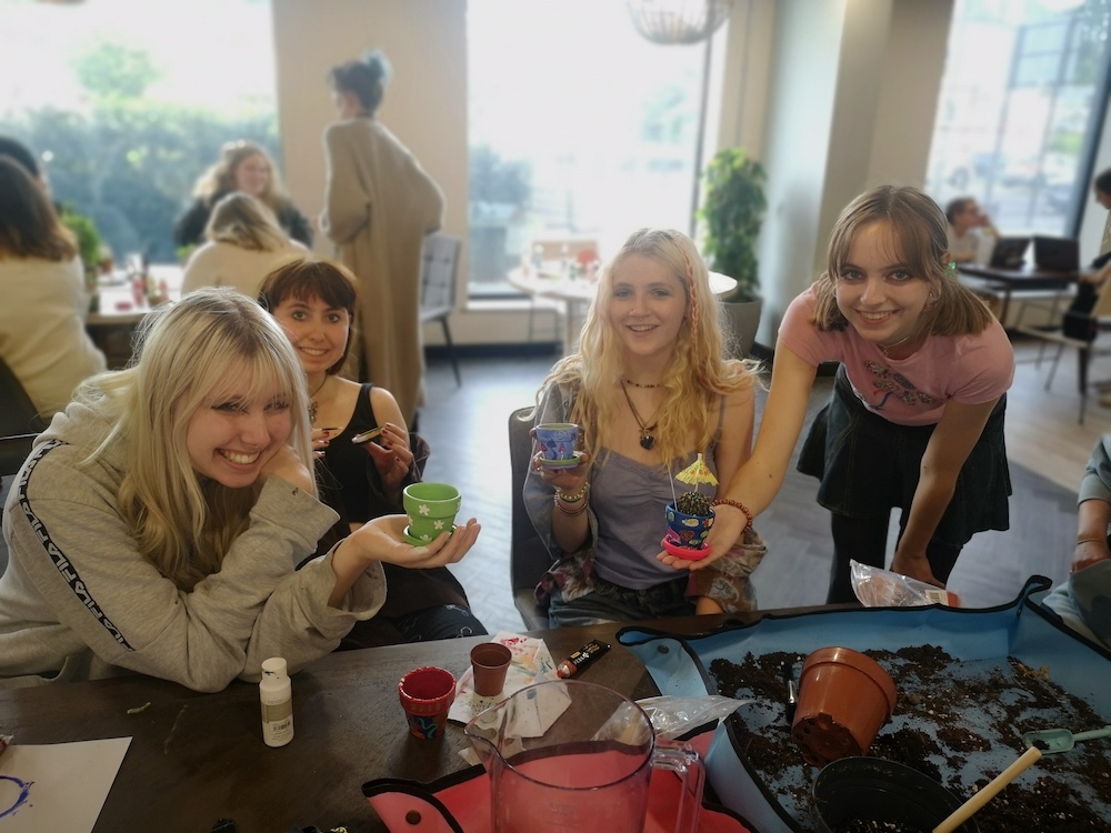 Four students sitting around a table and holding up patterned plant pots in their hands.