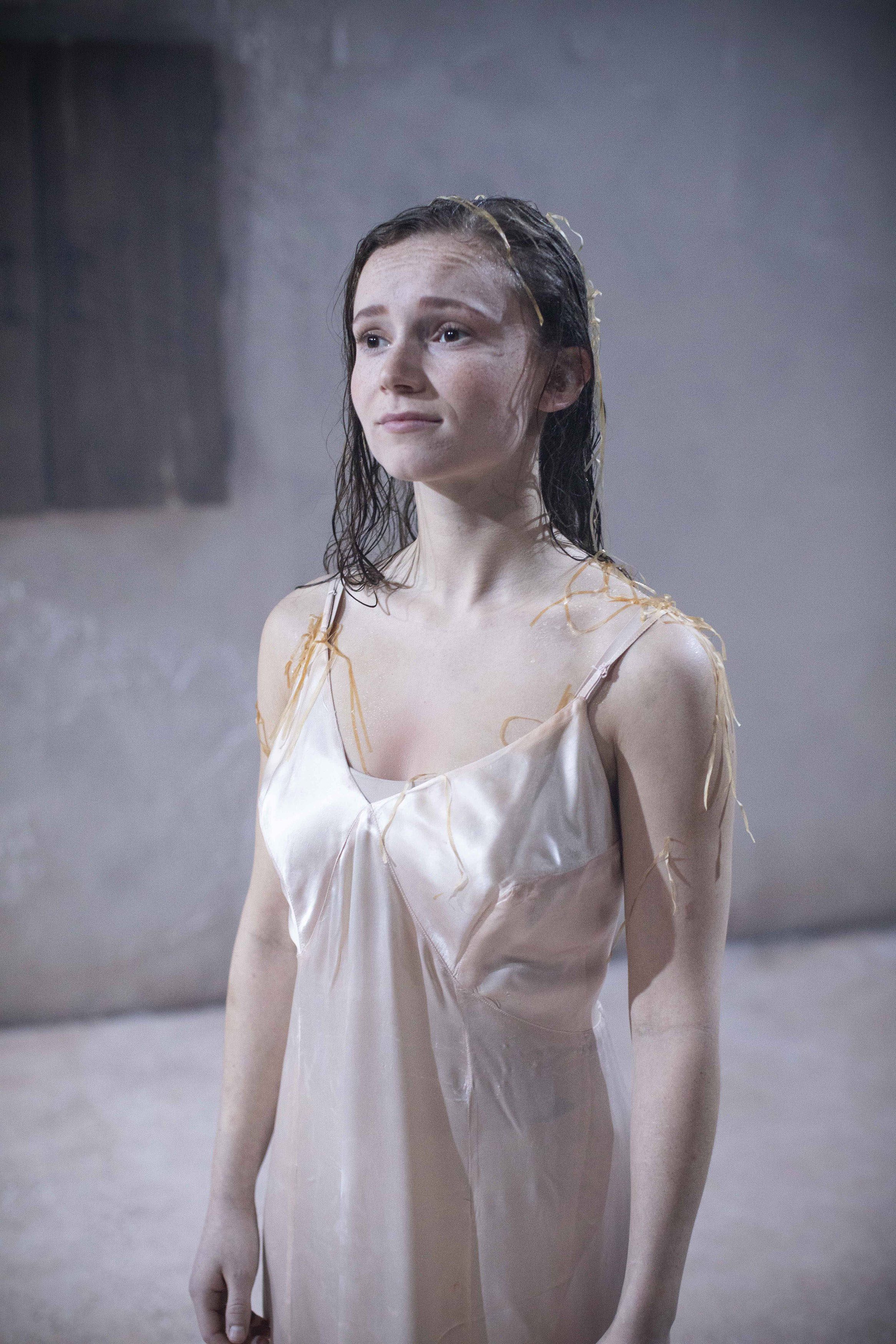 A person in costume in a nightie standing on stage.
