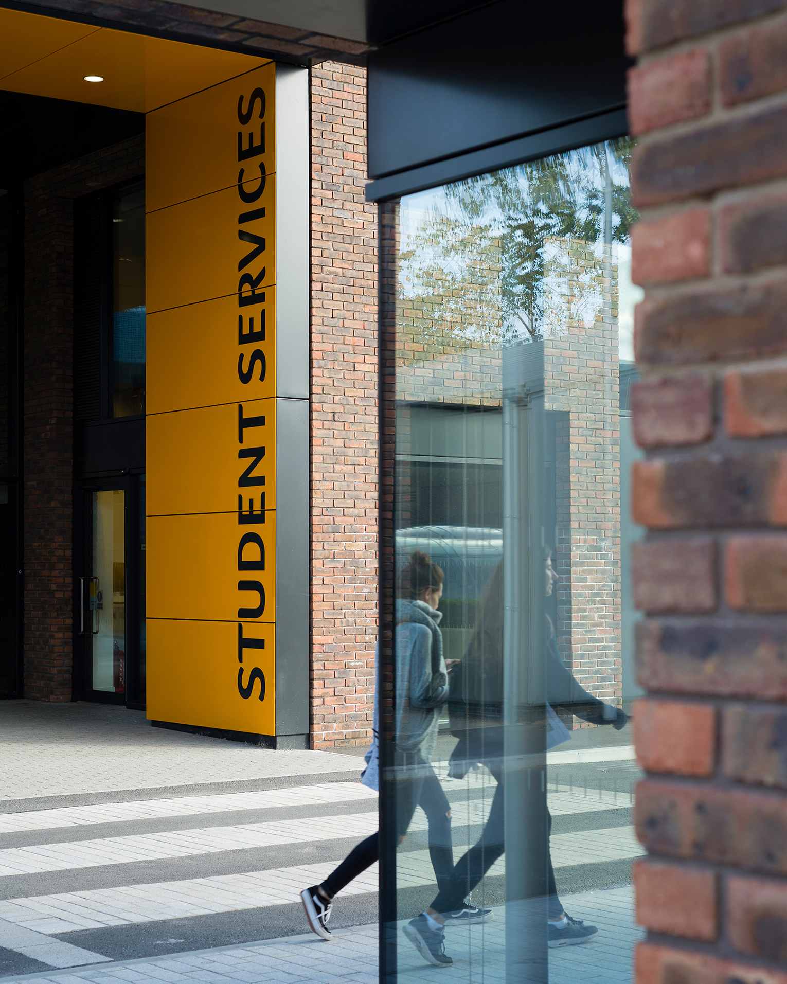 A pair of students walking past the Student Services building on AUB campus.
