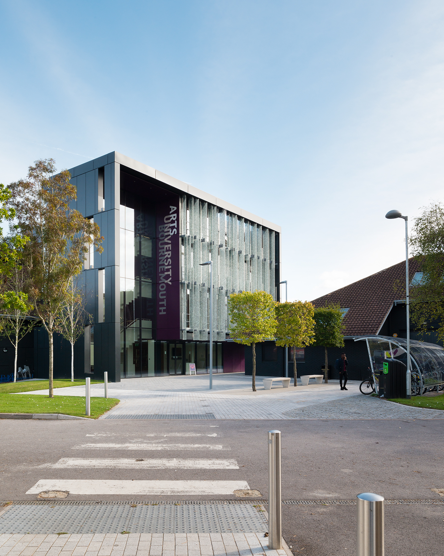 Two university buildings with square shaped trees in front of them.