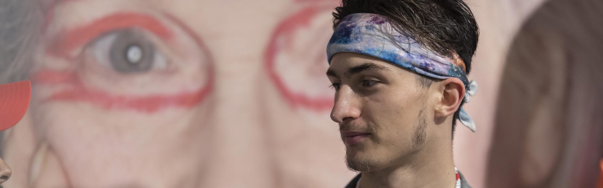 Close-up of an AUB student wearing a bandana standing in front of a mural.