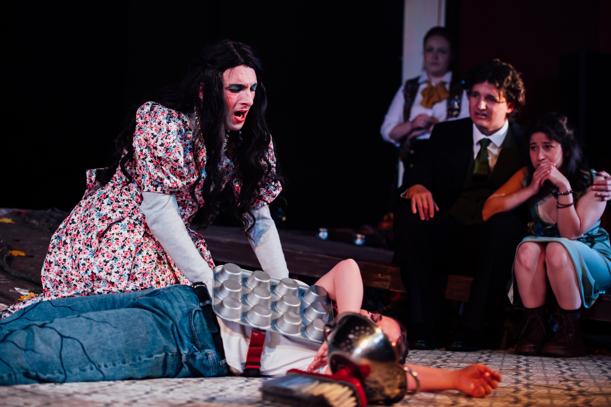 Actors on stage in A Midsummer Night's Dream surrounding a character on the floor.